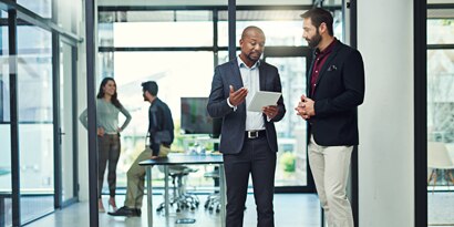 Man consulting tablet and explaining something to other man