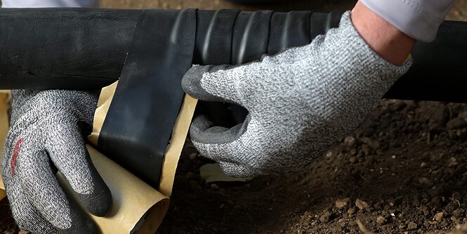 worker wrapping electrical cable in moisture sealing tape
