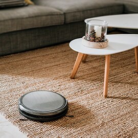 a wireless, robotic vacuum cleaning a living room carpet.