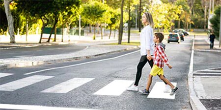 Woman and child confidently crossing the street at mid-block crossing with curb bump out and painted lines.
