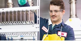 Person with safety glasses on looking at a machine in a lab.