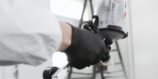 Video screen capture of person spraying paint with a paint gun.
