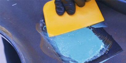 Applying Fiberglass resin with matting on vehicle part.
