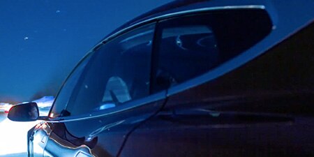 The driver's side of a sedan at night.
