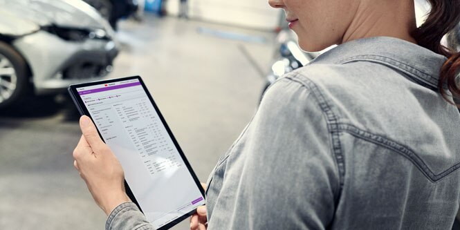 A woman looks closely at an invoice on a tablet device.
