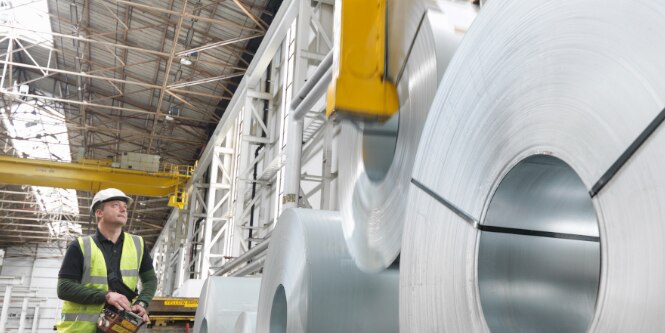 Worker moving sheet metal rolls
