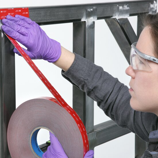 Woman applying 3M™ VHB™ foam tape to a meta frame for a commerical vehicle.