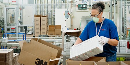 A person packing 3M products into a box in a manufacturing facility
