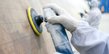 Person metalworking a steel surface with Cubitron Abrasives.
