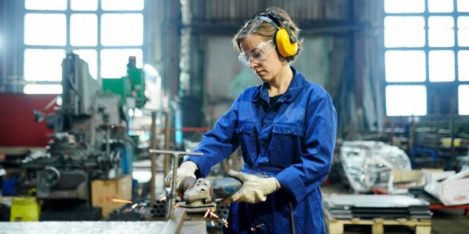 Woman in metal fabrication shop cutting metal
