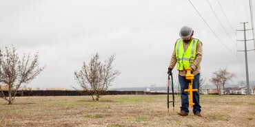 Field technician in a bright yellow protective safety vest pathmarking.