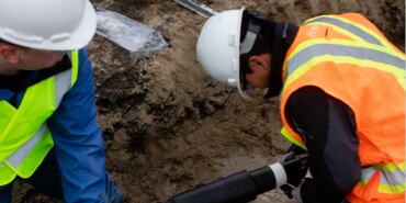 Two electrical workers working on a cable.