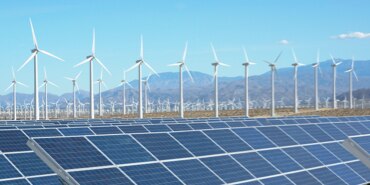 Arrays of wind turbines with multiple arrays of solar panels in the foreground.