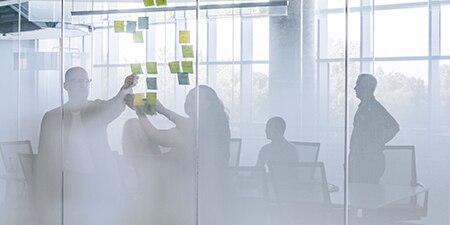 An outside perspective of a meeting in a frosted-glass conference room
