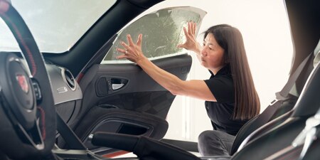 Installer applying a 3M Automotive Window Film to a car window
