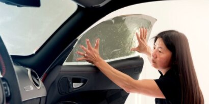 woman installing a window tint on the inside of a car window
