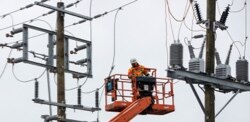An electrical worker in a lift close to power lines.
