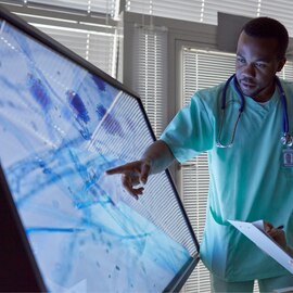 A medical professional pointing at a large screen showing medical results.