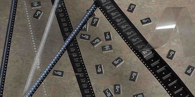 Tape and reel packaging on a grey background.
