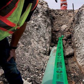 image of open trench with green ems caution tape for waste water industry