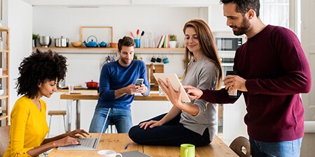A group of coworkers collaborating while using multiple types of consumer devices.
