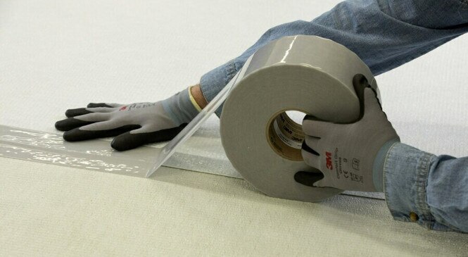 A worker applies tape to a panel seam

