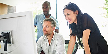 Three people in an office looking at a large screen.
