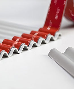 Image of 3M™ VHB™ Tape being applied to a sheet of corrugated metal
