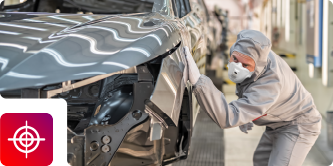 An automotive worker in protective gear inspects a gray vehicle body, featuring a target precision icon.
