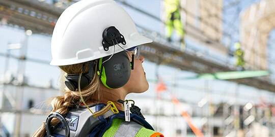 worker with hard hat and ear muffs looking away
