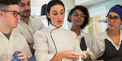 head chef training her team on restaurant food preparation
