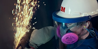 worker wearing 3M reusuable respirator and faceshield while grinding

