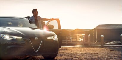 man staring into the distance next to her parked car.
