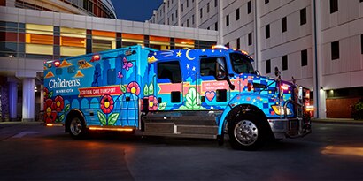 A hospital vehicle has a brightly colored graphic wrap that reflects light at nighttime.
