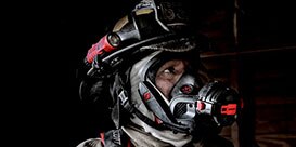 firefighters walking through a smokey building
