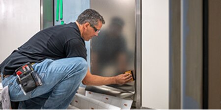 Employee installing an architectural finsih to a door.
