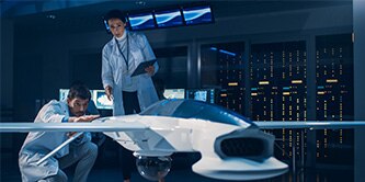 Two people in white lab  coats looking at a model of an airplane