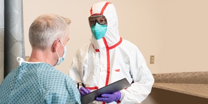 Patient with doctor wearing protective clothing and mask
