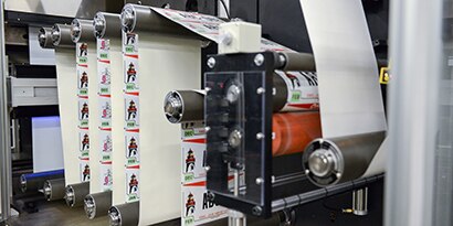 A long roll of license plate sheeting cycles through a large printer.
