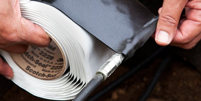 worker wrapping cable splice in electrical tape
