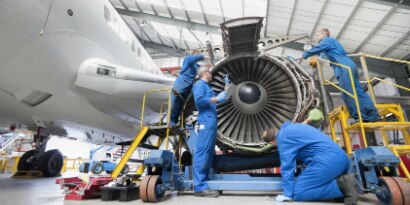 Engineers assembling engine of passenger jet in hangar
