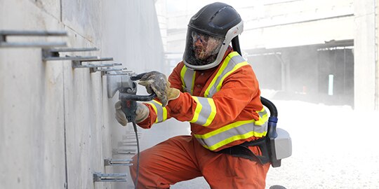 Worker wearing 3M protective equipment while cutting concrete.
