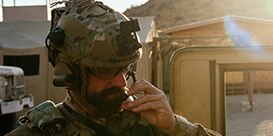 man in military garb speaking into protective comms microphone
