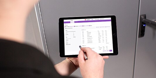 A person uses a digital pen on a tablet device showing the RepairStack software.
