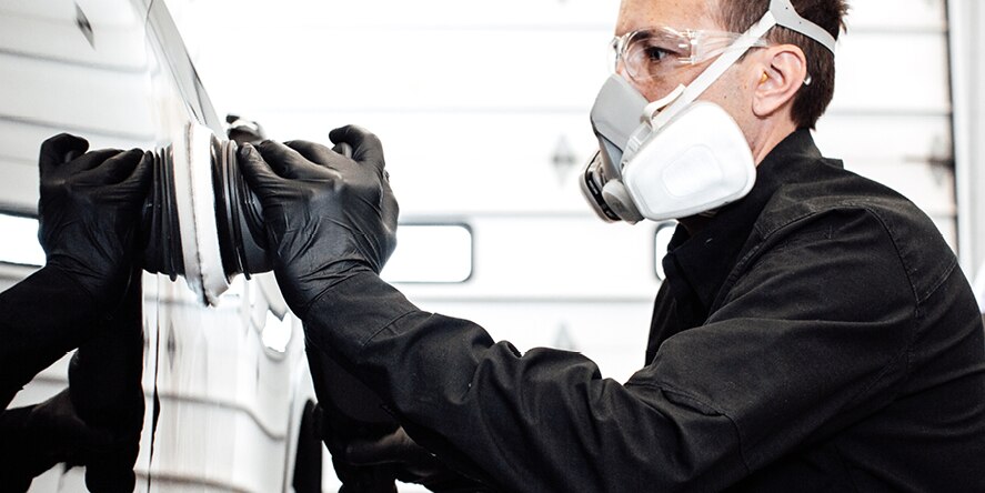 A technician uses the 3M™ Perfect-It™ Random Orbital Polisher on the side of a vehicle.
