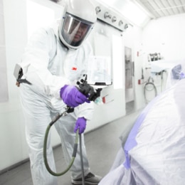 Man spraying paint onto a side car.