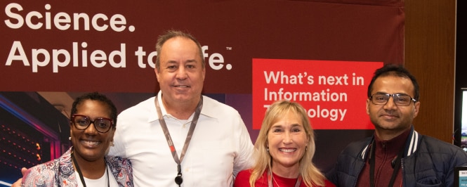 A group of four employees standing together at a 3M event.

