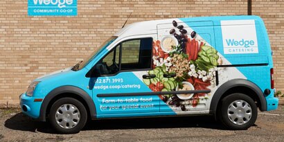A delivery van’s vehicle wrap displays graphics and images to support its brand.
