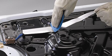 gloved hand applying acoustic material
