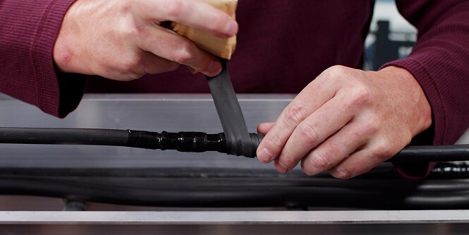 worker wrapping electrical splice with primary insulation tape
